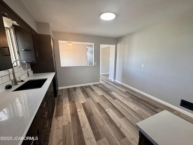 kitchen featuring dark brown cabinetry, sink, and light wood-type flooring