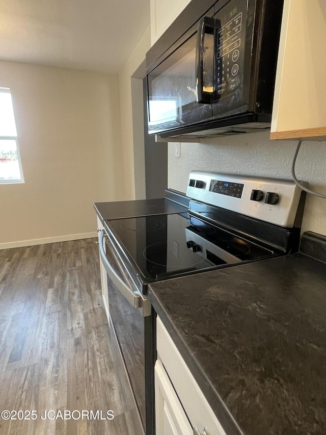 106 S Main St, Chamois, MO 65024 - kitchen featuring stainless steel electric stove, black microwave, wood finished floors, dark countertops, and baseboards