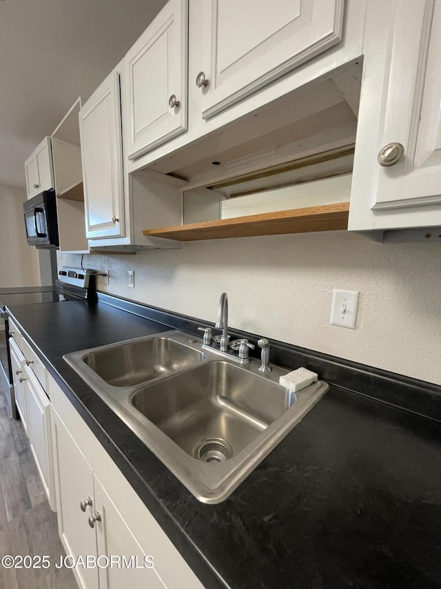 106 S Main St, Chamois, MO 65024 - kitchen featuring open shelves, a sink, dark countertops, white cabinetry, and black microwave