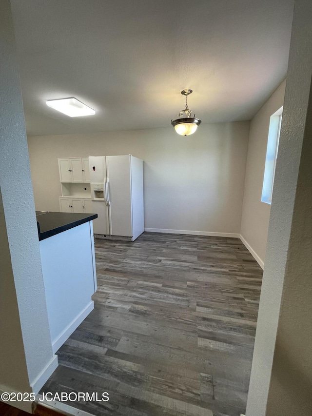 106 S Main St, Chamois, MO 65024 - kitchen with white fridge with ice dispenser, dark countertops, dark wood-type flooring, and baseboards