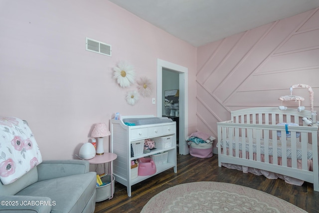 bedroom with dark wood-type flooring and a nursery area