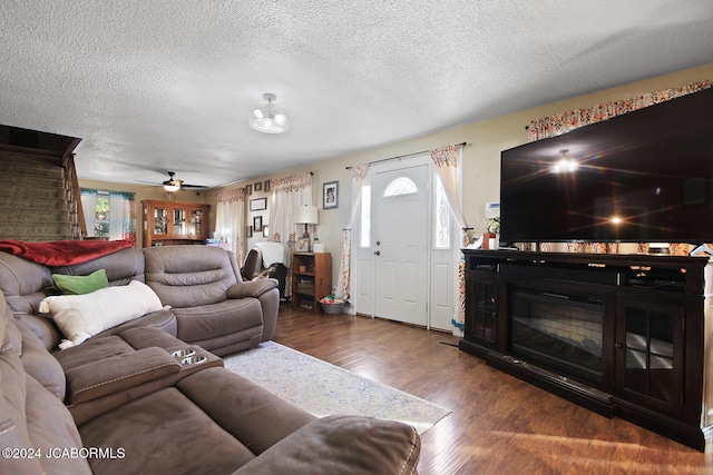 living room with ceiling fan, dark hardwood / wood-style flooring, a textured ceiling, and a wealth of natural light