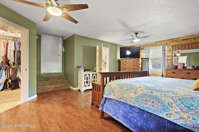 bedroom featuring hardwood / wood-style floors, ceiling fan, a spacious closet, a textured ceiling, and a closet