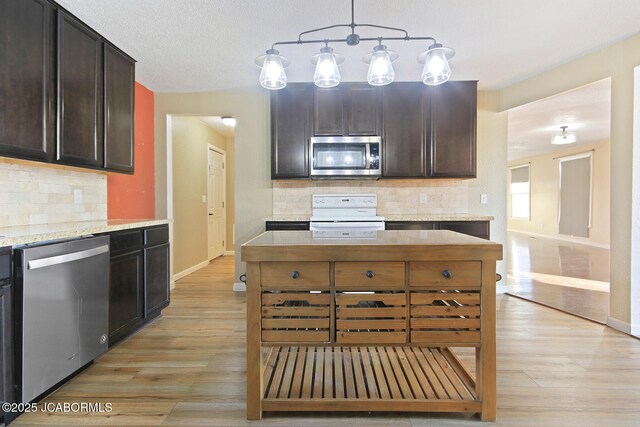 kitchen featuring decorative backsplash, dark brown cabinetry, stainless steel appliances, and light stone counters