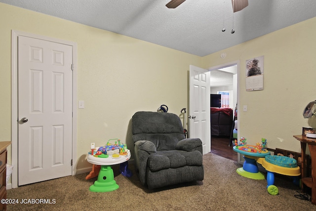 game room with ceiling fan, dark carpet, and a textured ceiling