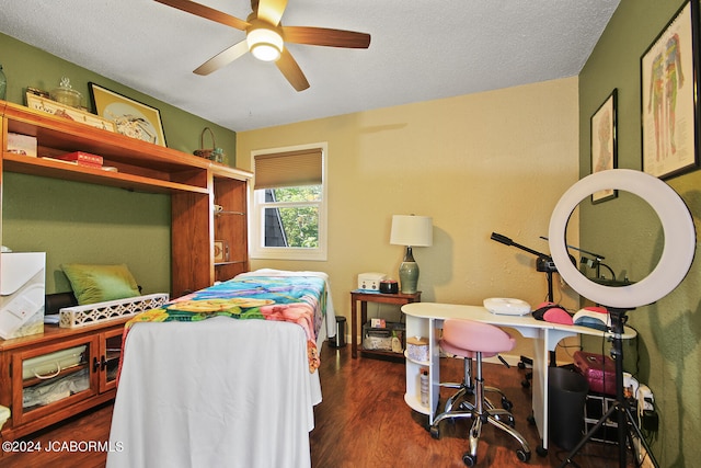 bedroom with a textured ceiling, ceiling fan, and dark wood-type flooring