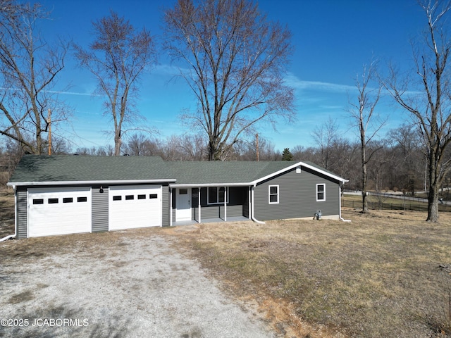 view of front of property featuring dirt driveway, roof with shingles, and a garage