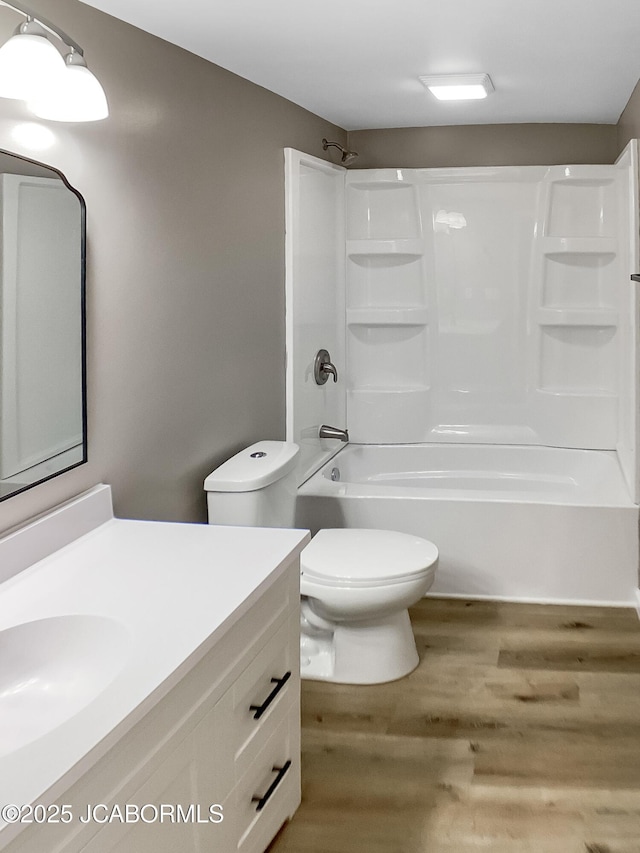 full bath with washtub / shower combination, vanity, wood finished floors, and toilet