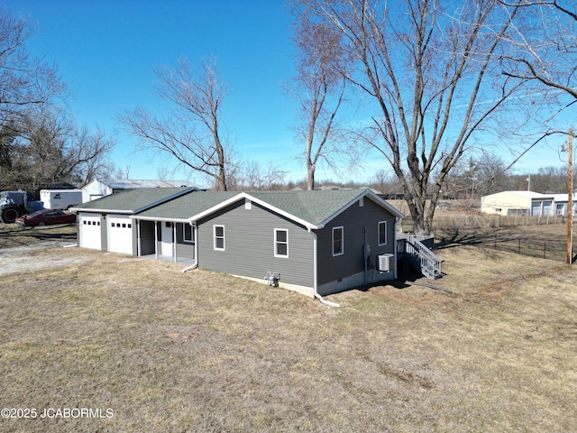 view of home's exterior featuring a garage, driveway, a shingled roof, fence, and a yard