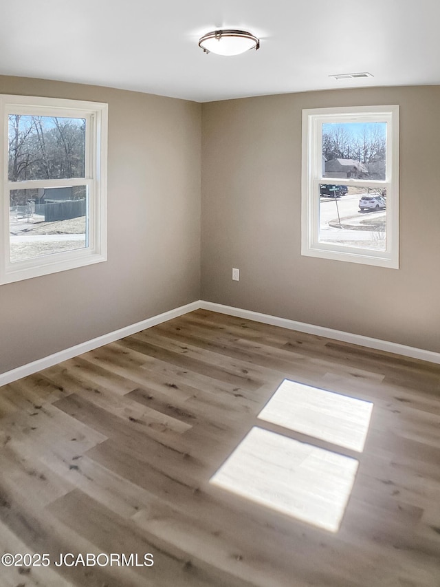 spare room with visible vents, baseboards, and wood finished floors