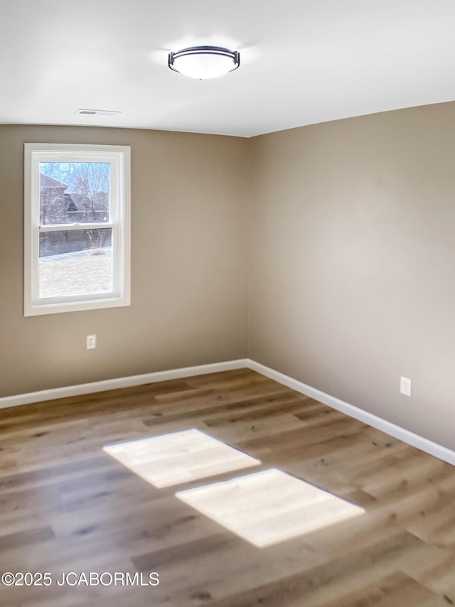 spare room featuring baseboards and wood finished floors