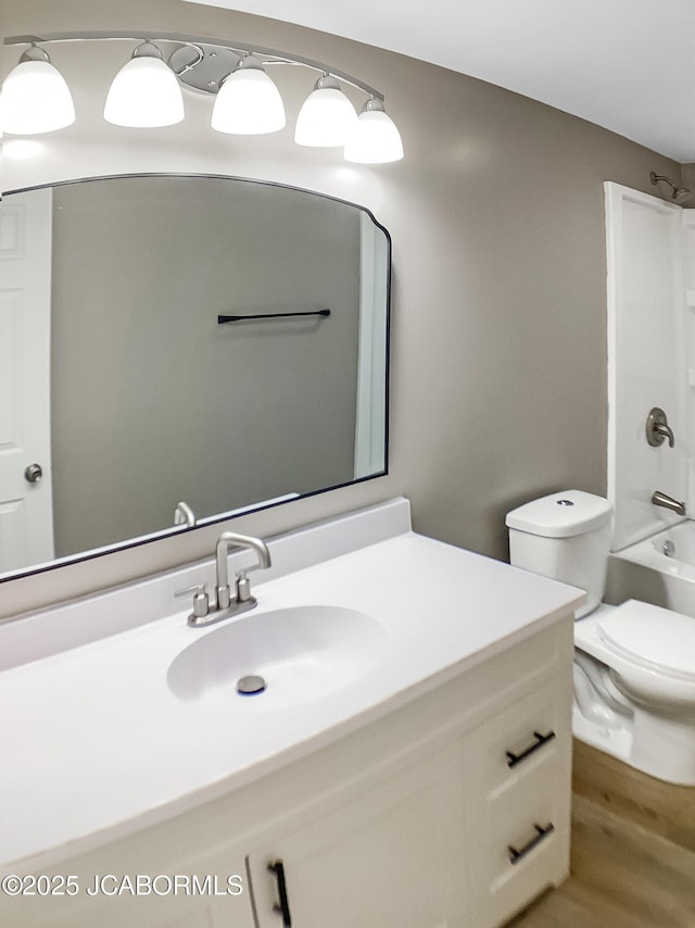 bathroom featuring toilet, bathtub / shower combination, wood finished floors, and vanity