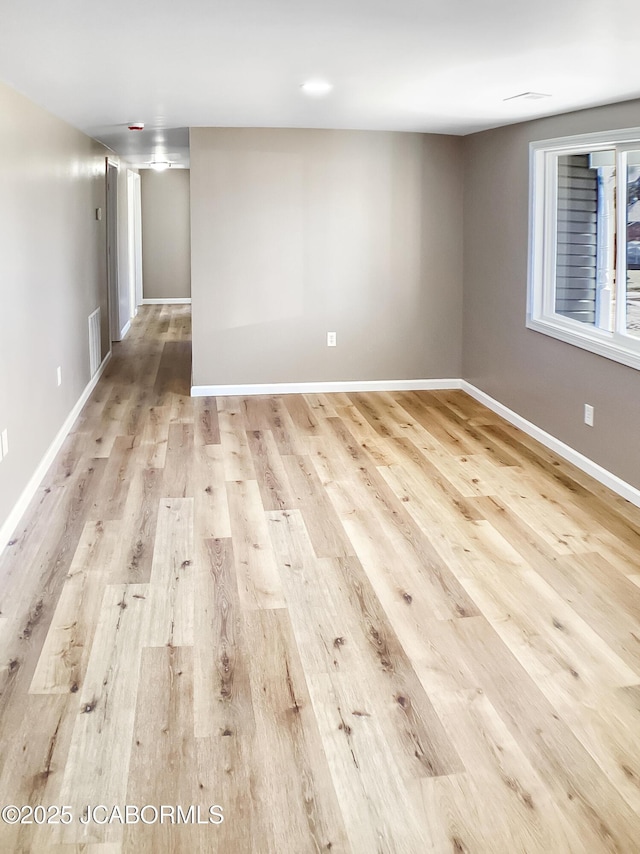 unfurnished room featuring baseboards, visible vents, and wood finished floors