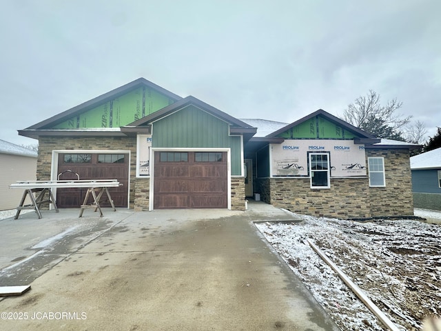 view of front facade featuring stone siding, driveway, and an attached garage