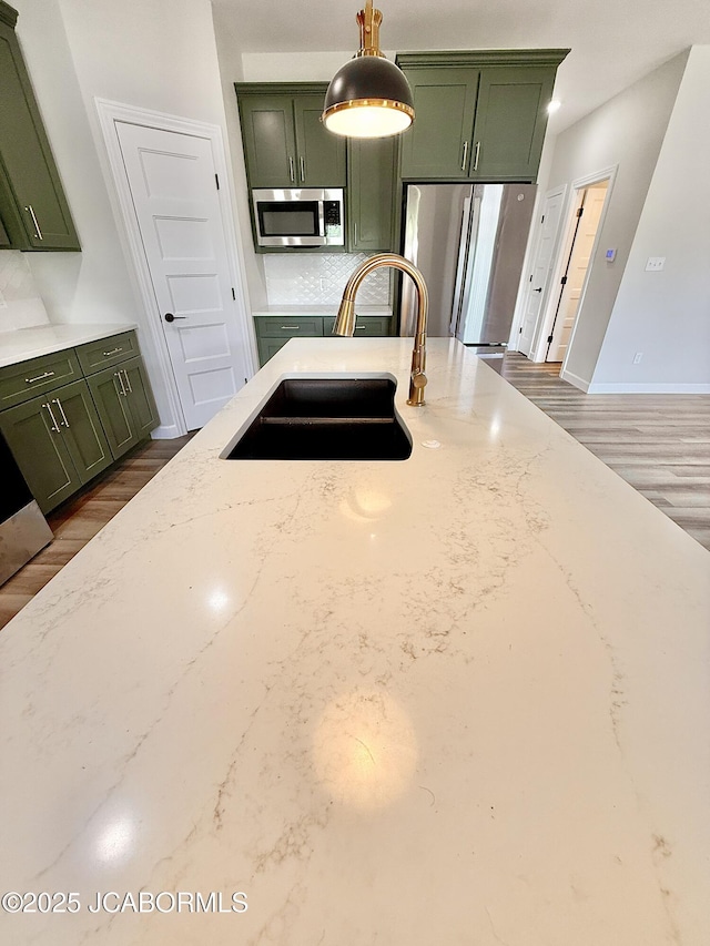 5519 Kenview Dr, Jefferson City, MO 65109 - kitchen with a sink, dark wood finished floors, light stone countertops, green cabinets, and appliances with stainless steel finishes