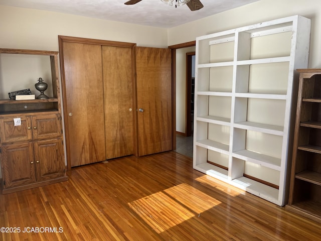 unfurnished bedroom featuring ceiling fan and dark wood-type flooring