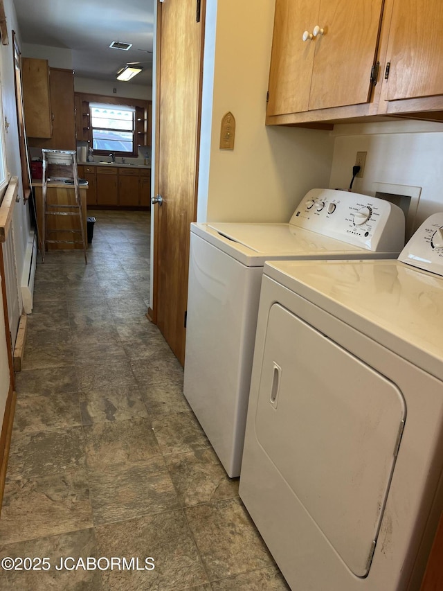 laundry area featuring separate washer and dryer, sink, cabinets, and a baseboard radiator