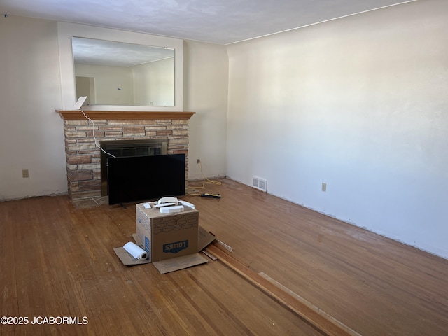 unfurnished living room featuring a stone fireplace and wood-type flooring