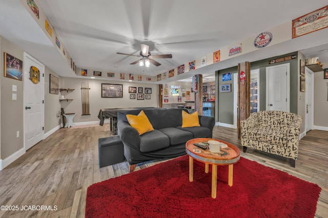 living area featuring baseboards, ceiling fan, and wood finished floors