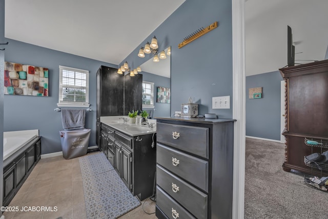 full bathroom with baseboards, a bath, lofted ceiling, and vanity