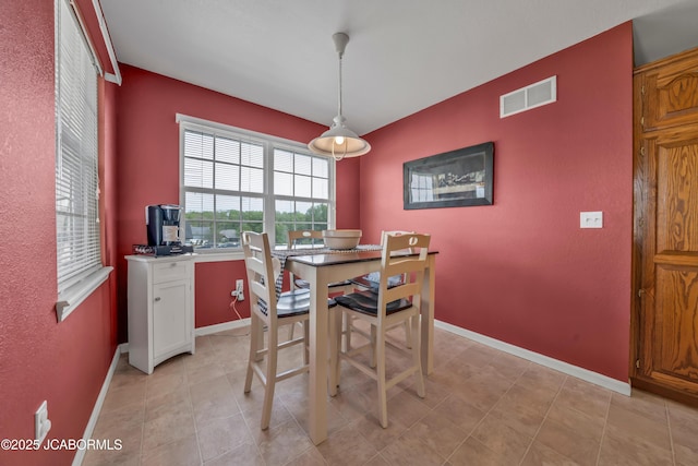 dining space with baseboards, visible vents, and an accent wall