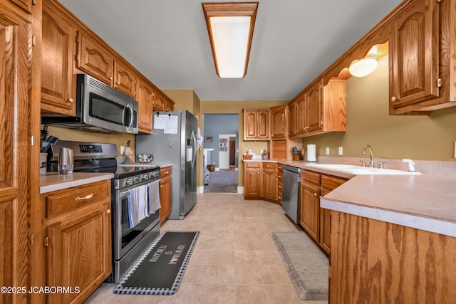 kitchen featuring light countertops, brown cabinetry, stainless steel appliances, and a sink