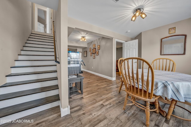dining room featuring baseboards, wood finished floors, and stairway