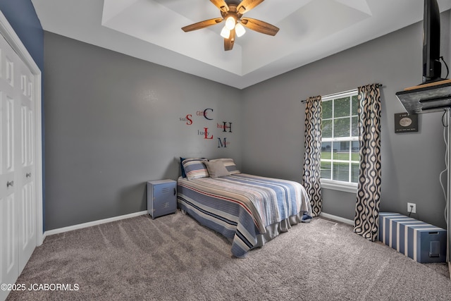 bedroom with carpet flooring, a tray ceiling, ceiling fan, and baseboards