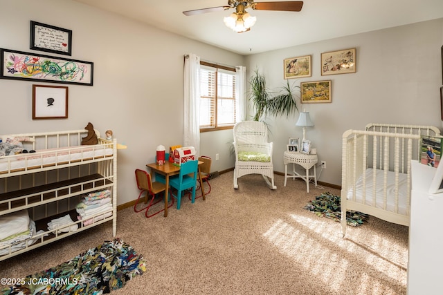 bedroom featuring a nursery area, carpet floors, and ceiling fan