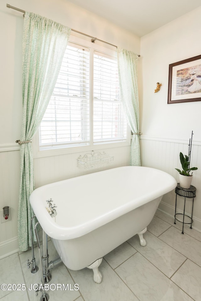 bathroom featuring a freestanding tub and a wainscoted wall