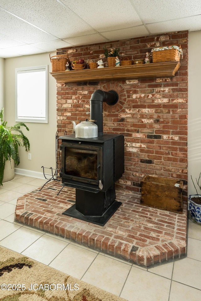 room details with a drop ceiling, a wood stove, and baseboards