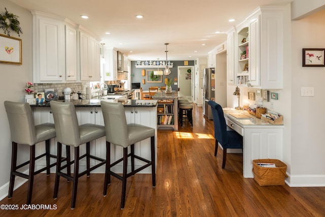 kitchen featuring white cabinetry, dark countertops, a peninsula, and freestanding refrigerator