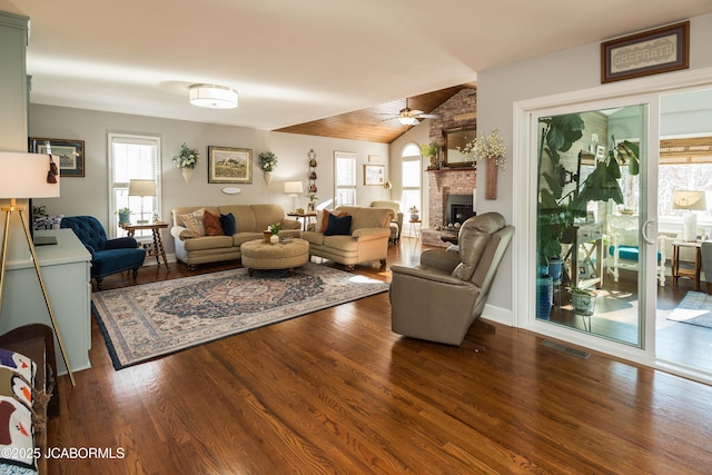 living room featuring visible vents, a brick fireplace, ceiling fan, vaulted ceiling, and wood finished floors