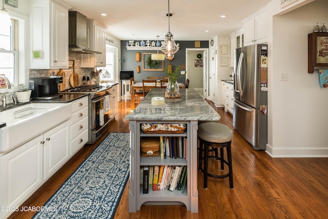 kitchen with stainless steel appliances, white cabinetry, a kitchen island, dark hardwood / wood-style flooring, and wall chimney range hood