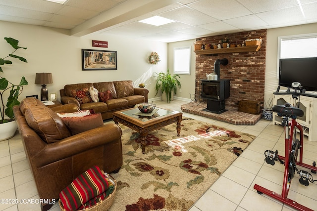 tiled living area with a wood stove, a paneled ceiling, and baseboards