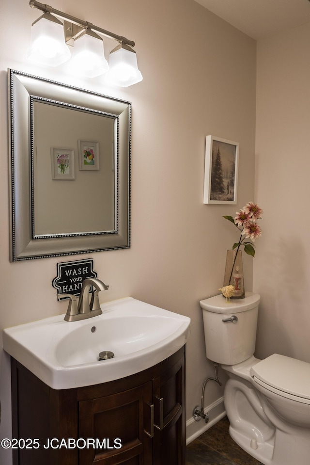 bathroom featuring baseboards, toilet, and vanity