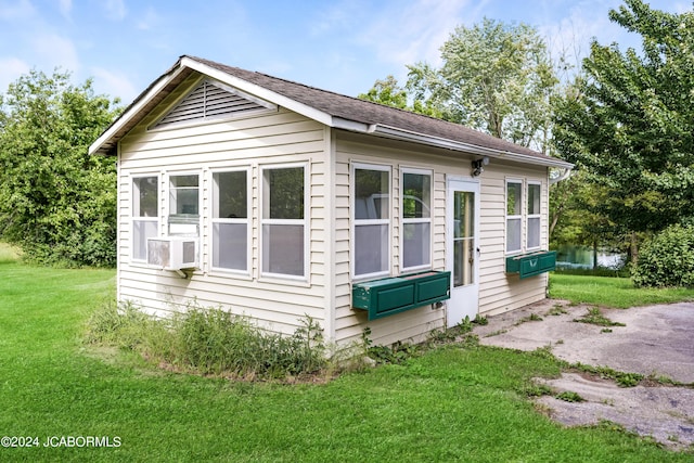 view of side of property with an outbuilding, cooling unit, and a lawn