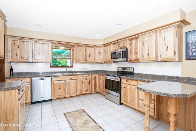 kitchen featuring sink, light brown cabinets, stainless steel appliances, dark stone counters, and light tile patterned flooring