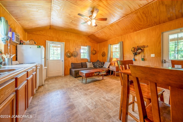 kitchen featuring white refrigerator, vaulted ceiling, ceiling fan, and wooden walls