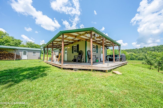 rear view of property featuring a lawn, an outdoor structure, and a wooden deck