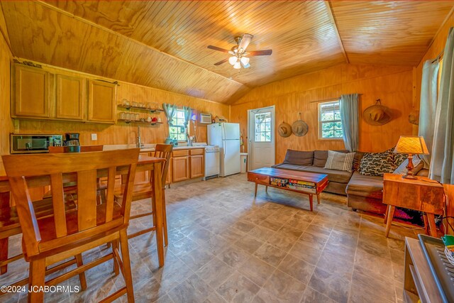 living room with sink, vaulted ceiling, ceiling fan, and wood walls