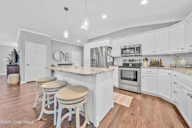 kitchen featuring stainless steel appliances, decorative light fixtures, a kitchen island, and white cabinets