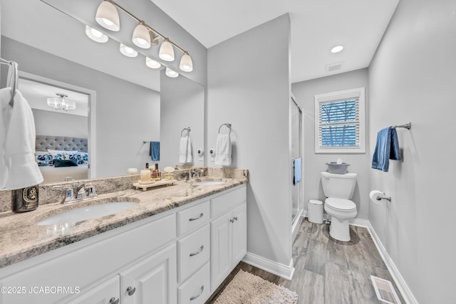 bathroom with vanity, hardwood / wood-style flooring, a shower with door, and toilet