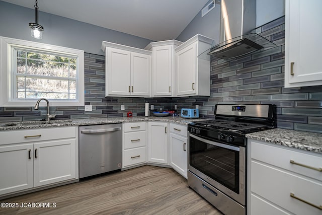 kitchen featuring sink, wall chimney range hood, white cabinetry, stainless steel appliances, and tasteful backsplash