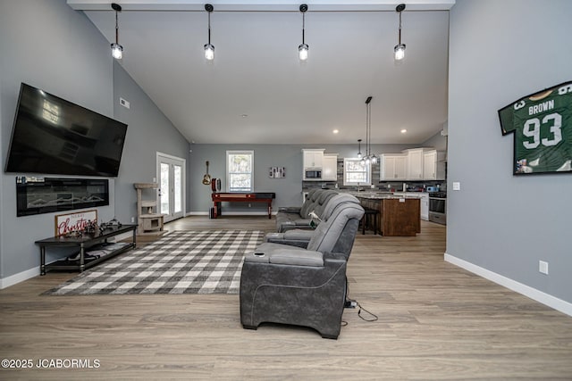 living room featuring high vaulted ceiling and light wood-type flooring