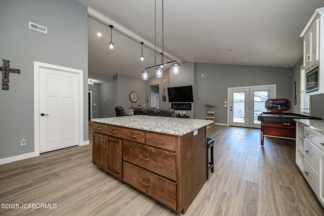 kitchen featuring white cabinetry, light stone countertops, light hardwood / wood-style floors, and a kitchen island