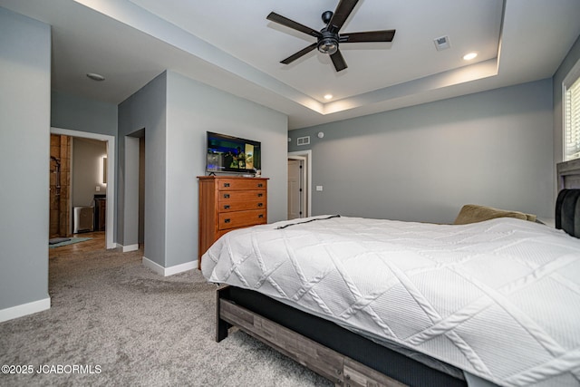 carpeted bedroom featuring a raised ceiling and ceiling fan