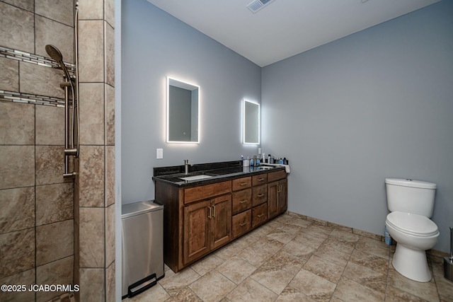 bathroom with vanity, toilet, and a tile shower