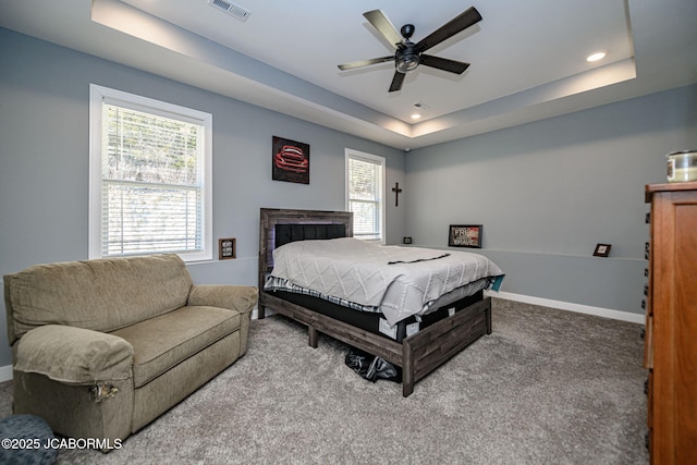 carpeted bedroom with ceiling fan and a raised ceiling