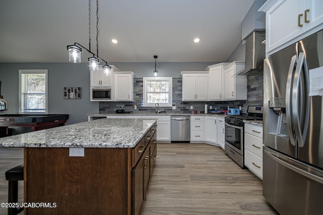 kitchen with pendant lighting, a kitchen island, white cabinets, and appliances with stainless steel finishes